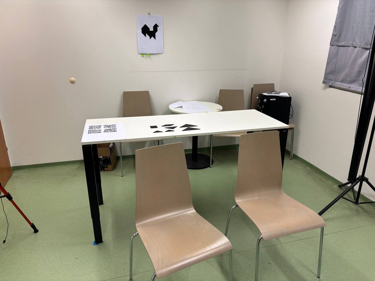 Study setup — table, tangram pieces, QR anchor, paper instructions on wall